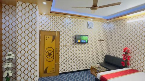 a room with a yellow door and a bed and a tv at Hotel Park Valley International in Ābdullāpur