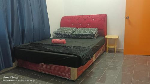 a bed with a red headboard and pillows on it at Anatolia Cottage in Wakaf Baharu