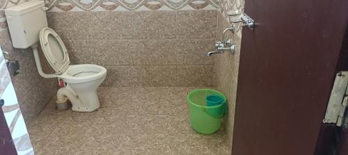 a bathroom with a toilet and a green bucket at SV HOMES Thiruvisanallur in Tribhuvanam