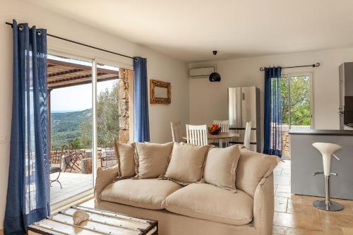 a living room with a couch and a sliding glass door at LAlpana in Figari