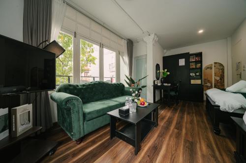 a living room with a green couch and a table at Chez Lumi Hotel in Hanoi