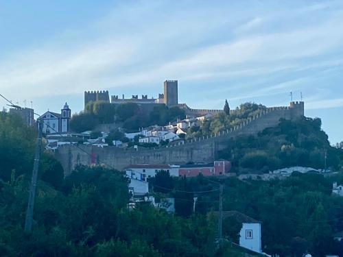 a castle on top of a hill with houses at CASAS LENTAS Slow Living-Óbidos in Sobral