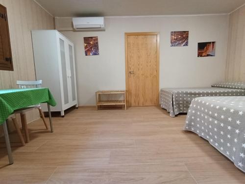 una camera con due letti e un tavolo e una porta di Habitación independiente II en Casa Rural Javier a Valmuel