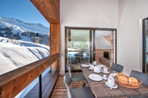 a table and chairs on a balcony with a mountain view at Turrabuel in Parpan