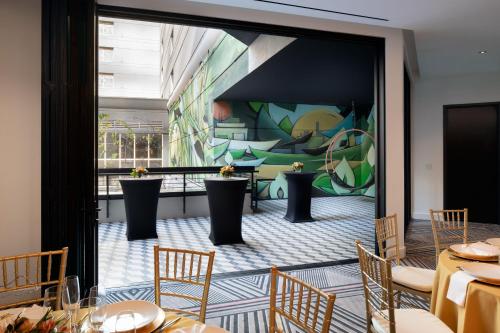 a restaurant with tables and chairs and a mural at The Clancy, Autograph Collection in San Francisco