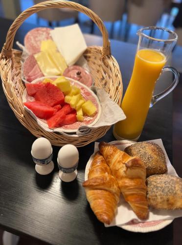 a table with a basket of food and bread and a glass of orange juice at Thatched country escape - Aarhus in Lystrup