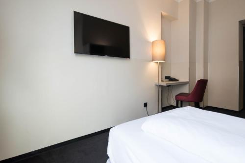 a hotel room with a bed and a tv on the wall at Hotel Topas Frankfurt City in Frankfurt/Main