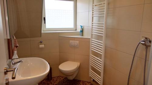 ein Bad mit einem Waschbecken, einem WC und einem Fenster in der Unterkunft Ferienwohnung Schuberski in Lipperreihe
