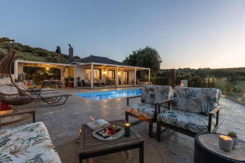 a patio with two chairs and a table and a pool at Villa Venia - Cozy Escape with Scenic Sew View, by ZanteWize in Tragaki