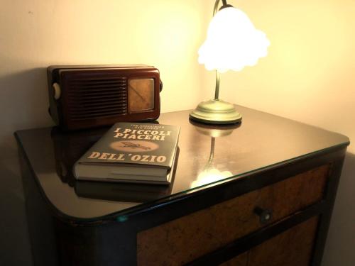 a table with a lamp and a book and a tv at Una casa ospitale con giardino in Castel SantʼAngelo