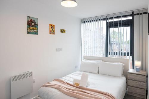 a white bedroom with a bed and a window at The Withington loft- Close To Uni's & Hospitals in Manchester