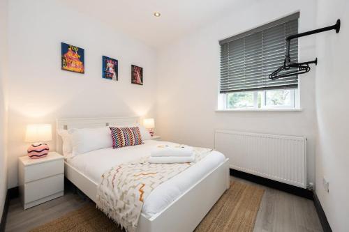 een witte slaapkamer met een bed en een raam bij The Didsbury Loft in Manchester