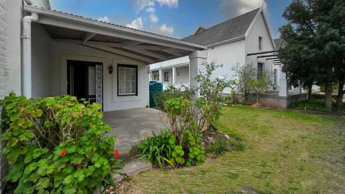 a white house with a yard with flowers at Old Posthouse Guest Accommodation in Ladismith