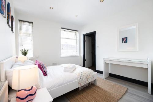 a white bedroom with a bed and a desk at The Didsbury Loft in Manchester