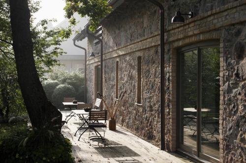 a stone wall with chairs and a table on a patio at Rumene Garden House in Rūmene