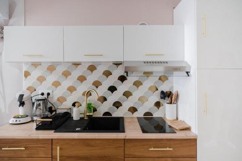 una cucina con mobili bianchi e un piano di lavoro di La Parenthèse Fleurie - Suite avec balnéo au coeur de Bergerac a Bergerac
