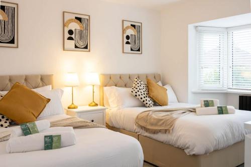 two beds in a room with white and yellow pillows at The Wilmslow House Free Parking - Close to Airport in Alderley Edge