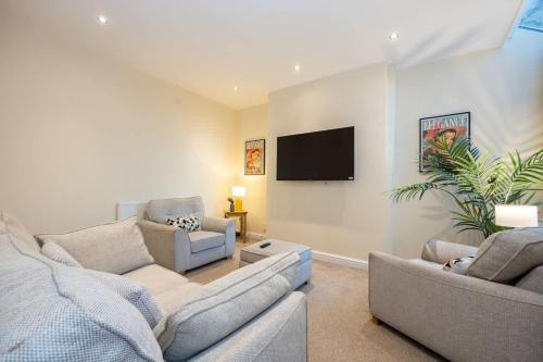a living room with two couches and a flat screen tv at Windmill House in Manchester