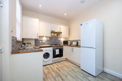 a kitchen with white cabinets and a white refrigerator at Windmill House in Manchester