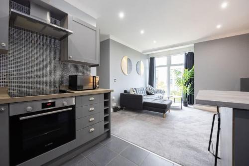 a kitchen and living room with a couch and a table at The Sharston - Free Parking & Close To Airport in Wythenshawe