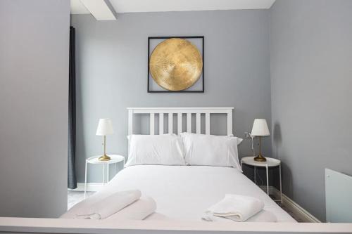 Un dormitorio con una gran cama blanca con dos lámparas. en The Sharston - Free Parking & Close To Airport, en Wythenshawe