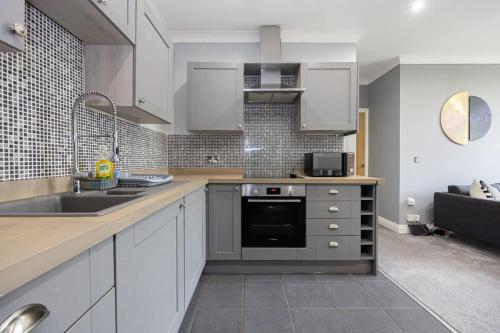 a kitchen with a sink and a stove top oven at The Sharston - Free Parking & Close To Airport in Wythenshawe