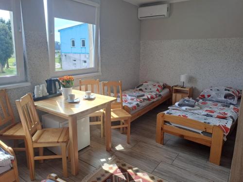 a small room with two beds and a table and chairs at Dom Wycieczkowy "Na stadionie" in Kłodzko