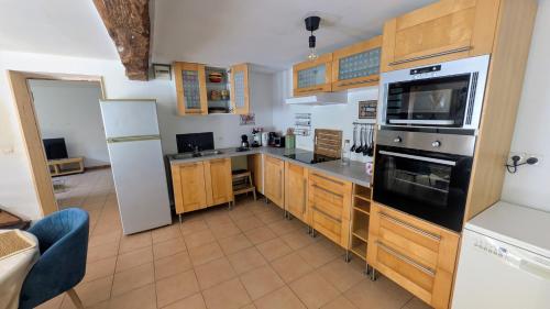 a kitchen with wooden cabinets and a white refrigerator at House - comfortable - spacious - 15' from Lille in Leers
