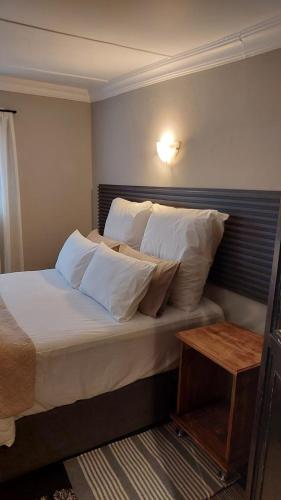 a bedroom with a bed with white sheets and pillows at Acorns and Quackers Self Catering in Underberg