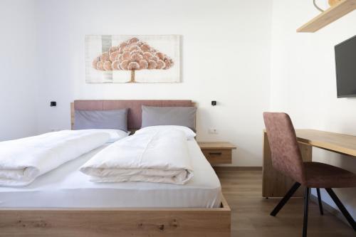 a bedroom with a bed and a desk and a chair at Pension Kleon in Rifiano