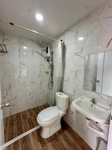 a white bathroom with a toilet and a sink at Bike Works Inn Bang Tao in Ban Thalat Choeng Thale