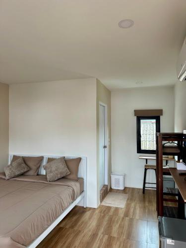 a bedroom with a couch and a table and a window at Bike Works Inn Bang Tao in Ban Thalat Choeng Thale
