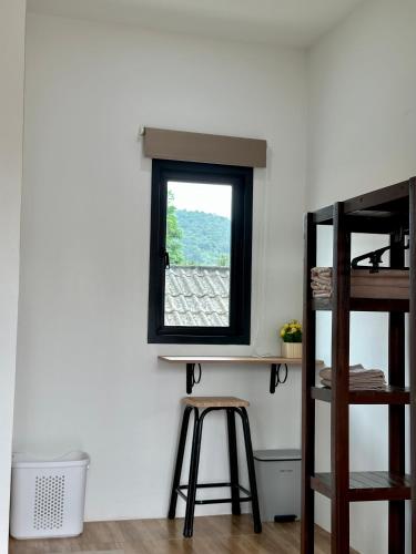a room with a window and a stool at Bike Works Inn Bang Tao in Ban Thalat Choeng Thale