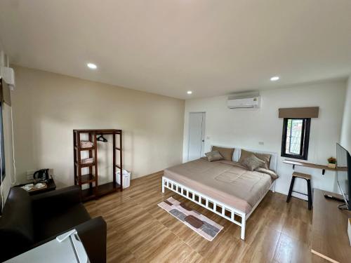 a bedroom with a bed and a living room at Bike Works Inn Bang Tao in Ban Thalat Choeng Thale