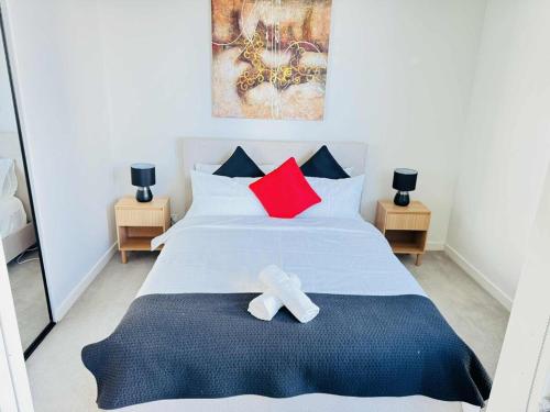 a bedroom with a bed with red and black pillows at ADEK Apartments North Melb - 2BR Apt near Melb Zoo with free Parking, Pool & Gym in Melbourne