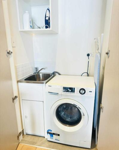 a washing machine in a kitchen with a sink at ADEK Apartments North Melb - 2BR Apt near Melb Zoo with free Parking, Pool & Gym in Melbourne