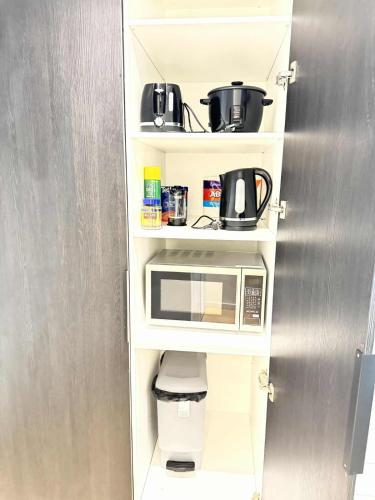 a kitchen with a white shelf with a microwave at ADEK Apartments North Melb - 2BR Apt near Melb Zoo with free Parking, Pool & Gym in Melbourne