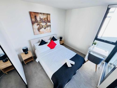 a bedroom with a white bed with red pillows at ADEK Apartments North Melb - 2BR Apt near Melb Zoo with free Parking, Pool & Gym in Melbourne