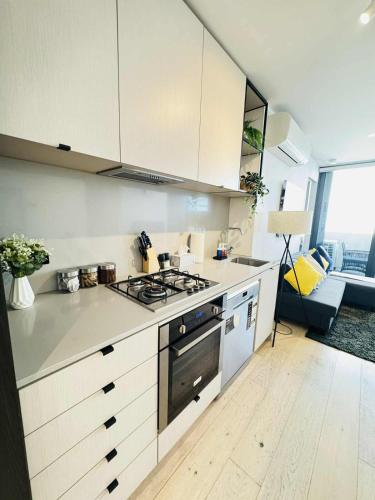 a kitchen with a stove top oven next to a couch at ADEK Apartments North Melb - 2BR Apt near Melb Zoo with free Parking, Pool & Gym in Melbourne