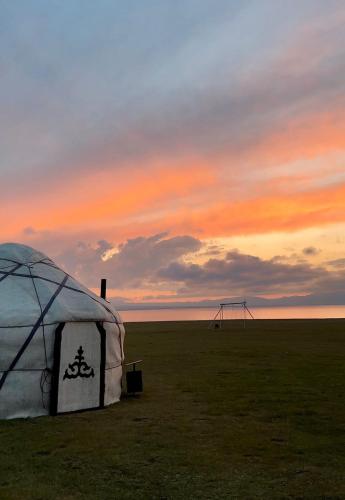 a tent in a field with a sunset in the background at Yurt Camp Ali-Nur, Lake Song-Kul , Kyrgyzstan, Юрточный лагерь Али Нур, на берегу озера Сон Кол in Naryn