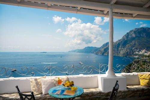 a table with a teddy bear sitting on top of a balcony overlooking the ocean at Villa Santa Chiara Positano Suites in Positano