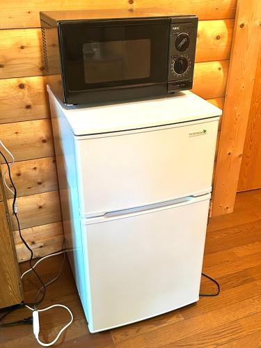 a microwave sitting on top of a refrigerator at Secret Base Mysa シークレットベース ミーサ 星の街399 in Tsumagoi