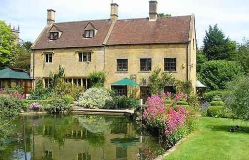 a large house with a pond in front of it at A Characterful Cotswolds Mill in Moreton in Marsh