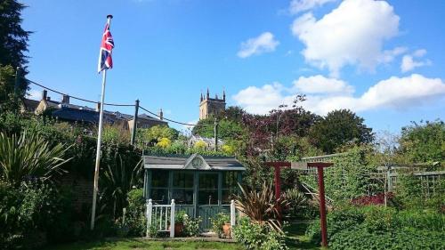 a house with an american flag in a garden at A Characterful Cotswolds Mill in Moreton in Marsh