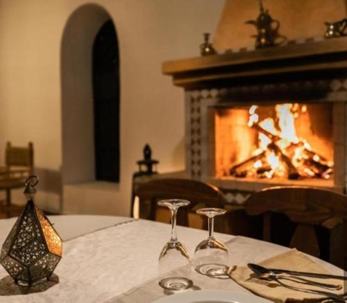 a table with two wine glasses in front of a fireplace at Mouhayut in Hassilabied