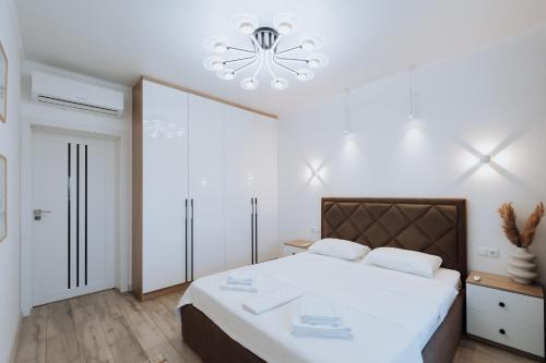 a bedroom with a large white bed with a chandelier at Modern Stay Rîșcani, AC, WiFi, Washer in Chişinău