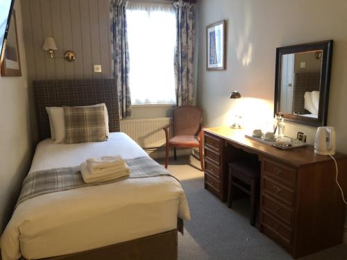 a bedroom with a bed and a desk and a mirror at The Old Bell - Warminster in Warminster