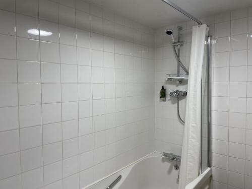 a white tiled bathroom with a tub and a shower at The Old Bell - Warminster in Warminster