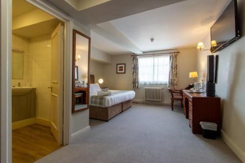 a room with a bedroom with a bed and a desk at The Old Bell - Warminster in Warminster