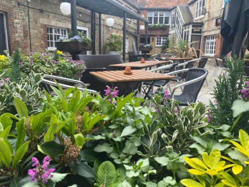 a patio with tables and chairs and flowers at The Old Bell - Warminster in Warminster